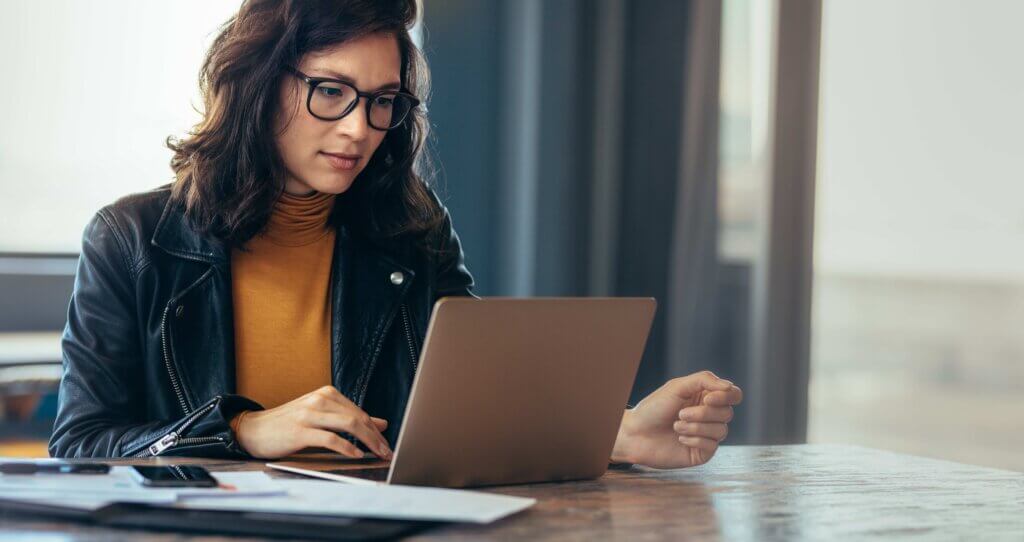 Woman with glasses working on laptop.